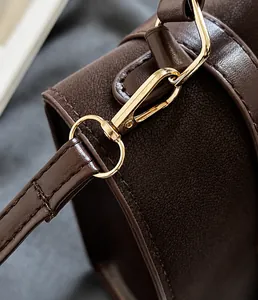 Macro-opname van een gepolijste gouden haak en gedetailleerd stiksel op een bruine leren tas