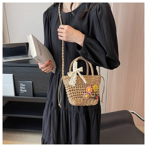 Detail of straw woven bucket bag featuring 3D floral accents and delicate lace bow