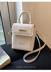 Detail of off-white PU leather bag with golden rivets and metallic lock hardware