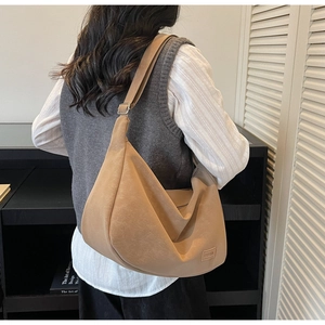 Détail de l'écusson FASHION sur un grand sac hobo en cuir mat de couleur camel