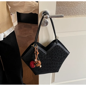 Detail of leopard print tote bag with V-shaped opening and plush pendant on door