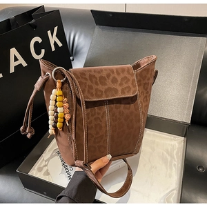 Macro view of leopard print suede bucket bag with contrast stitching and beaded charm