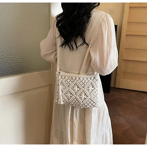 Detail of white handmade macrame crossbody bag featuring geometric patterns and long tassels