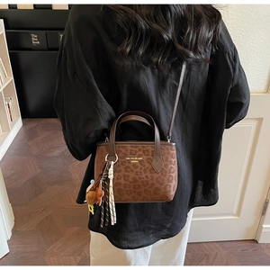 Brown leopard print tote bag with removable shoulder strap and woven star charm details