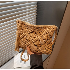 Close-up of handmade macrame straw envelope bag with decorative tassel and zipper
