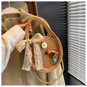 Detail of round straw bag with white lace bow, floral accents and wooden button