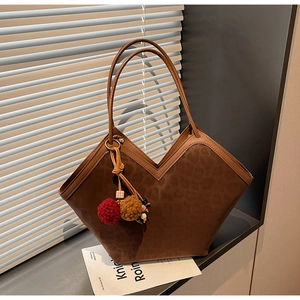 Detail of leopard print tote bag with plush charm on a window sill in soft lighting