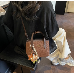 Close-up of leopard print tote bag with bear charm and adjustable shoulder strap