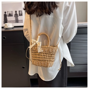 Close-up of straw woven bucket bag with lace bow detail and braided straps on model