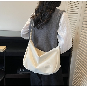 Détail du sac dumpling en cuir blanc crème avec étiquette FASHION et bandoulière réglable