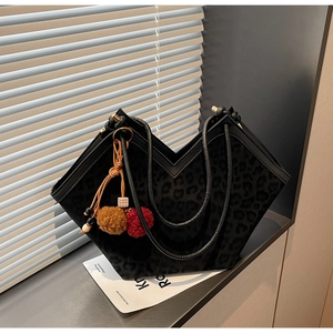 Macro detail of black leopard print tote bag with V-cut top and stylish tassel pendant