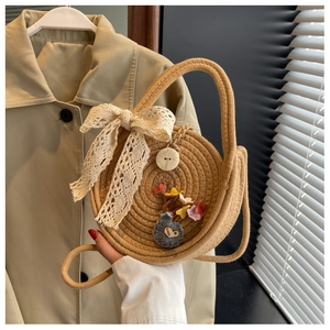 Close-up of handmade straw bag with lace bow and colorful felt flowers detail