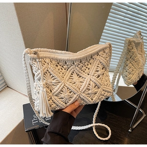 Close-up of white hand-woven straw bag with fringe tassel and metallic zipper detail