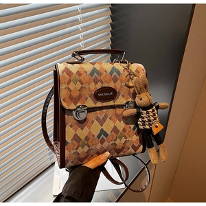 Detail view of a retro argyle crossbody bag with brown leather trim and a cute rabbit charm
