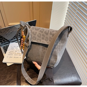 Detail of grey frosted suede bucket bag featuring leopard print flap and ethnic wooden beads