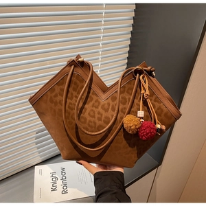 Detail of leopard print tote bag with V-shaped opening and plush ball charm accessory