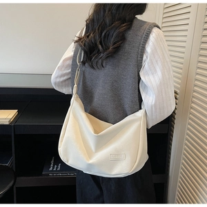 Détail d'un sac dumpling beige en similicuir souple avec logo fashion et bandoulière chic