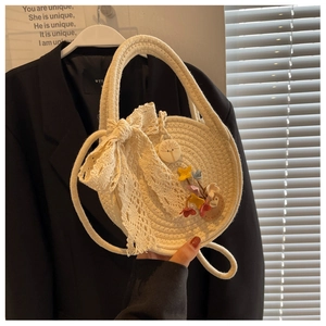 Detail of round straw bag featuring lace bow, fabric flowers and wooden button texture