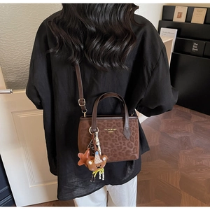 Detail of leopard print plush tote bag with gold logo and cute bear charm pendant