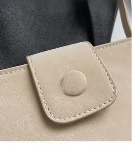 Détail du sac à main beige en similicuir avec texture grainée et fermeture à rabat bouclé