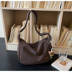 Détail du sac hobo marron avec étiquette en cuir et pendentif ours décoratif