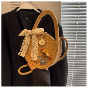 Detail of yellow straw woven bag featuring a white lace bow and floral embroidery