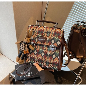 Detail of checkered tweed handbag with leather handle and cute plush rabbit charm