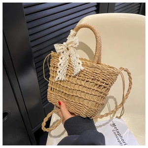 Detail of hand-woven straw bucket bag featuring a delicate white lace bow and fabric lining