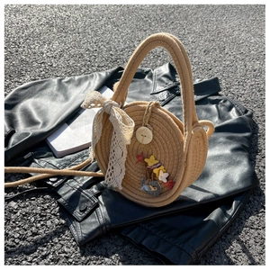 Detail of round straw bag with white lace bow and colorful felt flower decorations