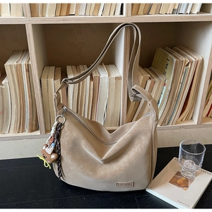Détail du sac beige avec étiquette en cuir et pendentif d'ours décoratif brun