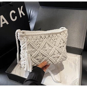 Detailed close-up of white macramé woven crossbody bag featuring tassels and zipper closure