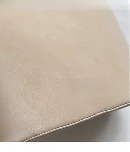 Gros plan d'un sac seau beige en cuir montrant le grain fin et les coutures soignées