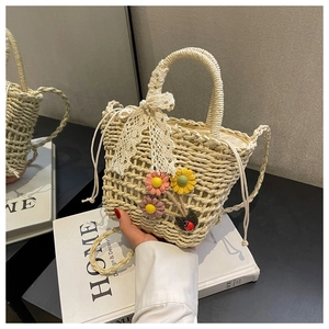 Detail of straw woven bucket bag with 3D floral accents and a delicate lace bow handle
