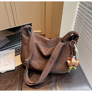 Détail d'un sac hobo en cuir marron avec étiquette mode et charmant porte-clés ours