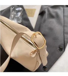 Detail of adjustable beige leather strap with gold metal buckle and smooth zipper closure