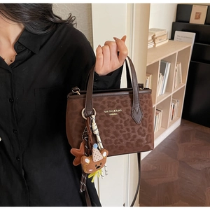 Close-up of leopard print tote bag with brown faux fur texture and cute bear pendant