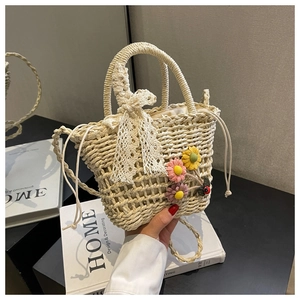 Close-up of woven straw bucket bag with floral crochet charms and elegant lace bow