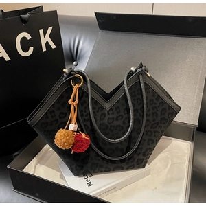 Detail view of large leopard print tote bag with plush charms in a luxury gift box