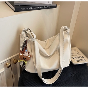 Détail macro du sac hobo en cuir PU beige avec texture et charm en peluche