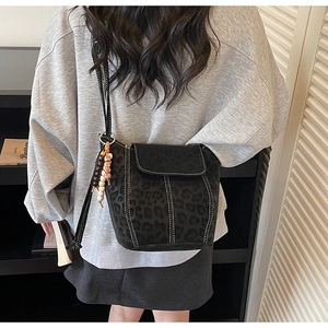Detail of black leopard print bucket bag with contrast stitching and tassel charm