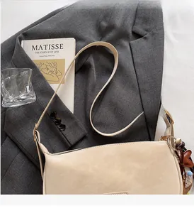 Detail view of cream leather dumpling bag featuring a sturdy handle and comfortable grip