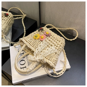 Close-up of woven straw bag with colorful floral embroidery and lace drawstring closure