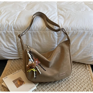 Détail d'un grand sac dumpling marron avec étiquette mode et charmant pendentif ours