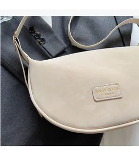 Detail of beige crescent shoulder bag with grain texture on grey blazer background