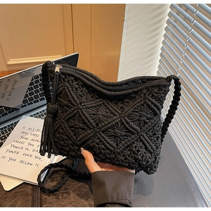 Detail of black macrame woven bag with diamond pattern, long side tassels and zipper closure