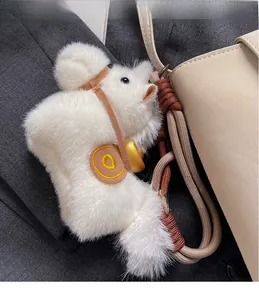 Détail d'un pendentif en peluche blanche avec lingot d'or et cordelette tressée
