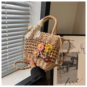 Close-up of handmade straw bucket bag with floral accents and lace bow detail