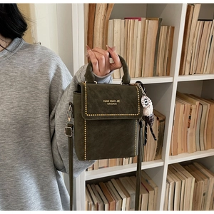 Detail of dark green retro handbag with gold studs and brand logo on matte leather