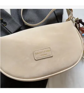 Detailed macro view of the cream beige dumpling bag featuring minimalist leather brand label