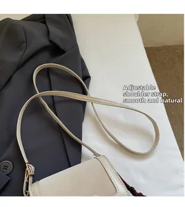 Detail of adjustable strap and metal hardware on cream minimalist crossbody bag